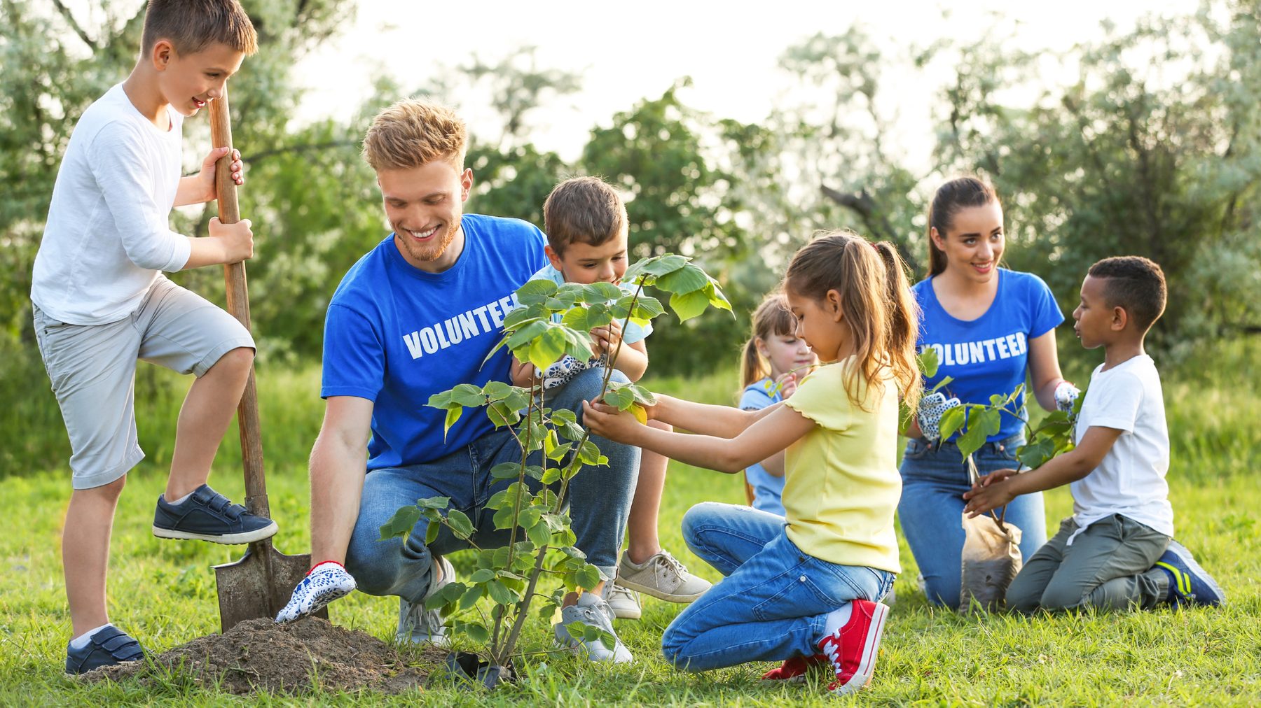 Volunteers and kids planting a tree together